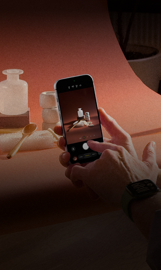 Séance photo dans un environnement professionnel, une personne utilise un iPhone pour photographier des produits sur un fond, une autre personne tient une lampe