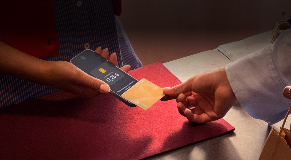 Une main approche une carte bancaire d’un iPhone pour finaliser une transaction