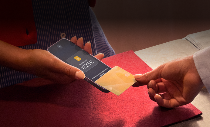 Une main approche une carte bancaire d’un iPhone pour finaliser une transaction