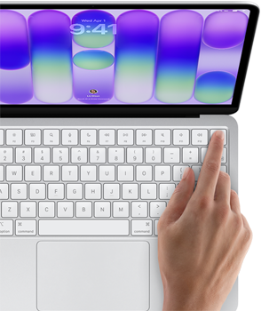 MacBook Neo, couleur argent, affichant l’écran de connexion, doigt d’une personne sur le capteur Touch ID situé dans le coin supérieur droit du clavier